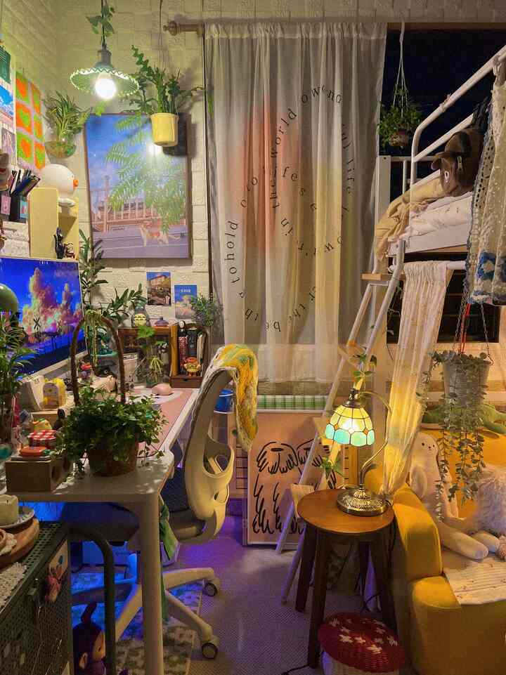 暖かみのあるイエローとベージュのトーンのロフトタイプの一人暮らしのホームオフィス兼寝室空間。ヴィンテージ照明と植物が調和する雰囲気のあるインテリア