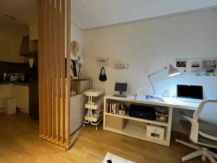 Bright white and wood tone small home office space with practical layout separated from kitchen by slatted partition