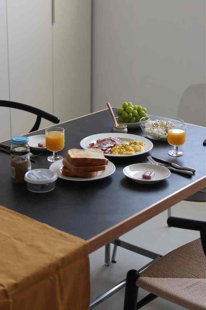 黒い天板と木目調のテーブルがあるダイニングルーム、食器と簡単な朝食が配置された印象的で温かみのある空間