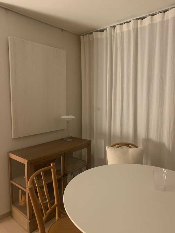 Natural wood tones and white hues feature a round dining table with chairs in a simple dining room setting