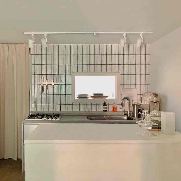 Modern white-toned kitchen featuring stainless steel sink and neatly arranged utensils with a clean atmosphere