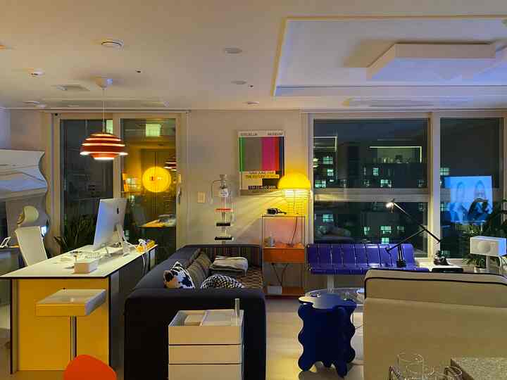 暖かい黄色の照明とモダンな家具が配置されたコンパクトなリビングルーム