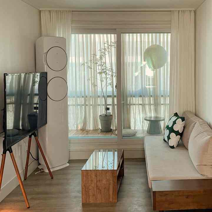 ホワイトとウッドトーンが調和した狭いリビング、ベランダとミニマルな家具が配置された自然な雰囲気のインテリア