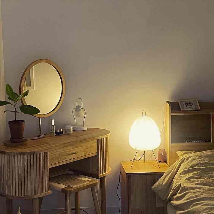 Natural wood tone bedroom featuring vanity desk, stool, bed, and warm table lamp creating cozy atmosphere