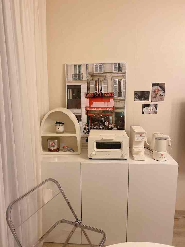 White-tone kitchen corner featuring Balmuda toaster, electric kettle, and Illy coffee machine creating a cozy home cafe space
