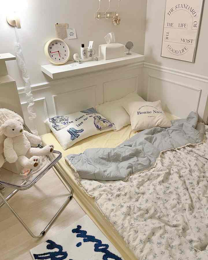White and beige toned bedroom featuring cozy bedding and a plush teddy bear, creating a warm atmosphere