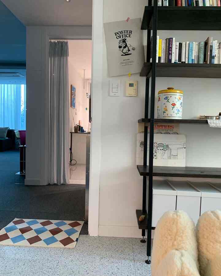 White and gray toned living room featuring bookshelf and checkerboard rug with modern atmosphere