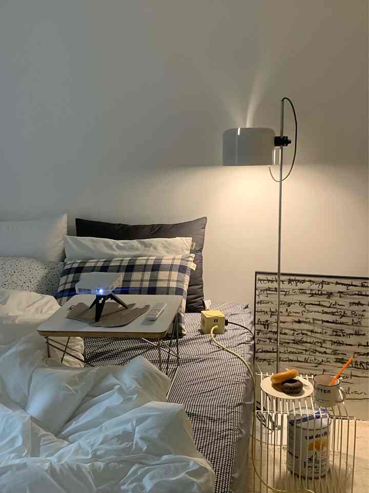 White and navy toned bedroom featuring a wireless mini projector, nightstand, and cozy atmosphere