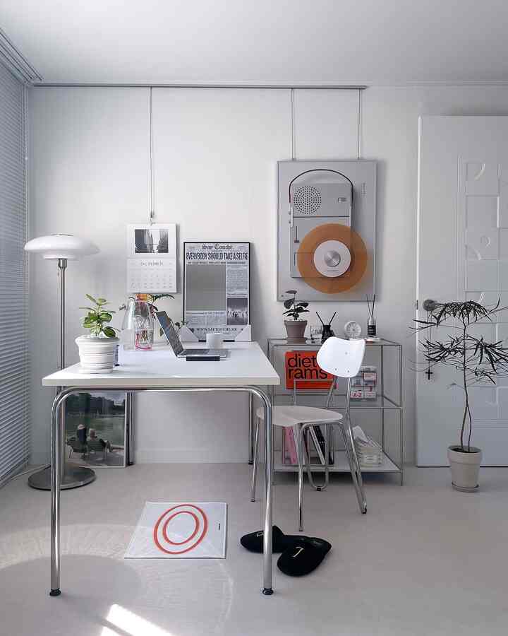 ホワイトとシルバーの書斎、机と椅子が配置され、ポスターと植物のある清潔感のあるホームオフィス