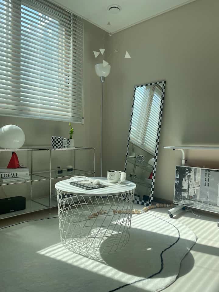 Bright white and natural toned living room featuring a white coffee table and a checkered full-length mirror centrally placed