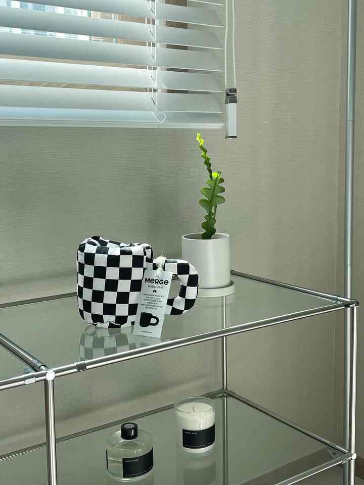 Natural beige-toned room featuring transparent glass shelving with a checkerboard accessory and cactus plant arranged on modular shelves