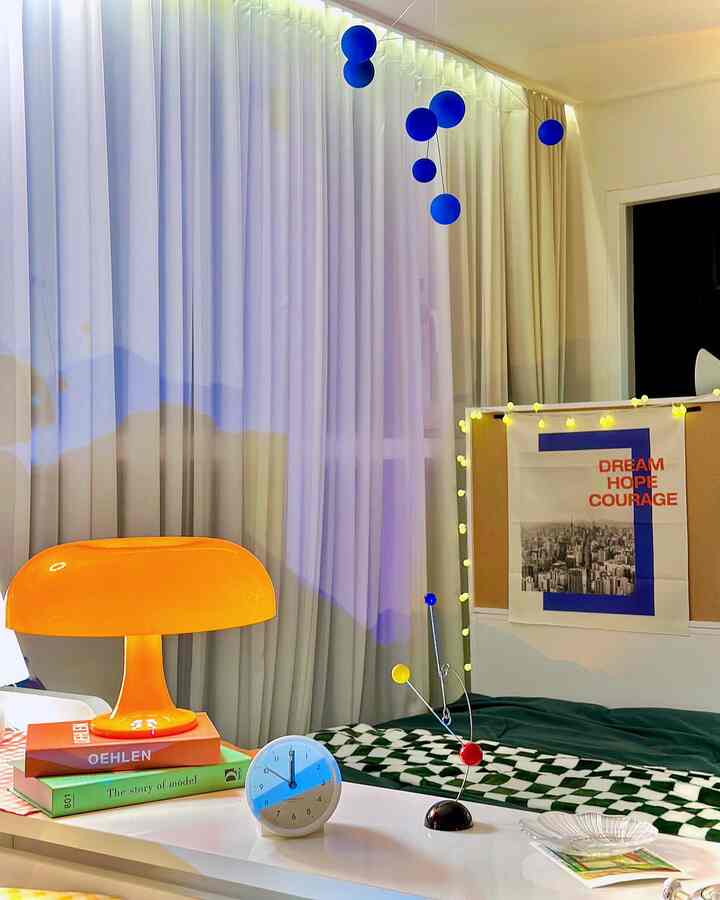 Bright orange table lamp and blue mobile in a Mid-Century Modern style bedroom space