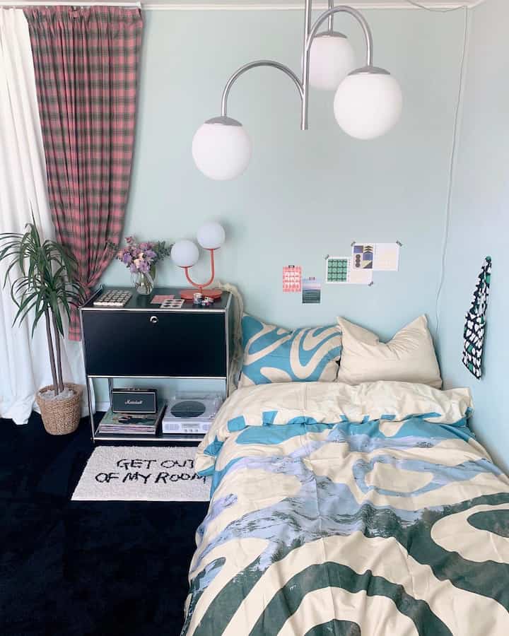 Pastel blue walls with white and pink checkered curtains in a bedroom featuring modular cabinet and patterned bedding creating a cozy atmosphere