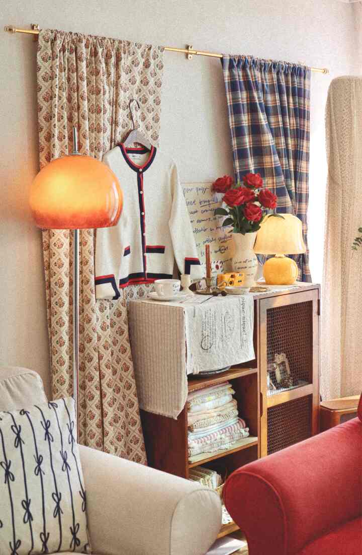 温かみのあるブラウンとアイボリーのリビング、ヴィンテージカーテンとスタンドライト、木製キャビネットが雰囲気あるインテリア