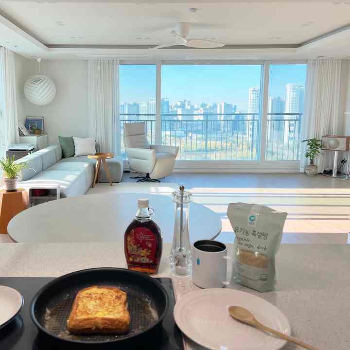 Bright white and beige toned living room and kitchen featuring modern, natural furniture with cozy atmosphere