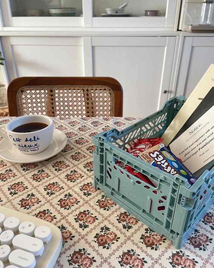 白い壁と茶色の椅子があるおうちカフェのダイニングテーブル空間、ミント色の収納ボックスとコーヒーカップが配置された雰囲気のあるインテリア