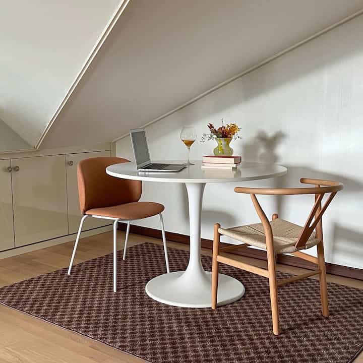 White and wood tone two-person dining space featuring round table and chairs in cozy small room interior