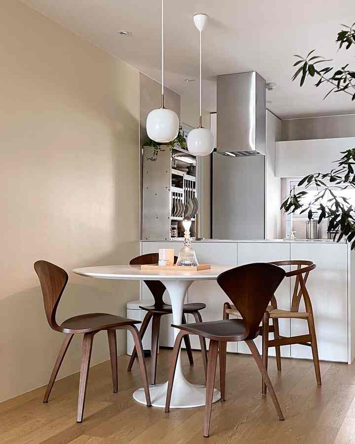 White and wood tone dining room with round dining table and pendant lights, showcasing a modern space