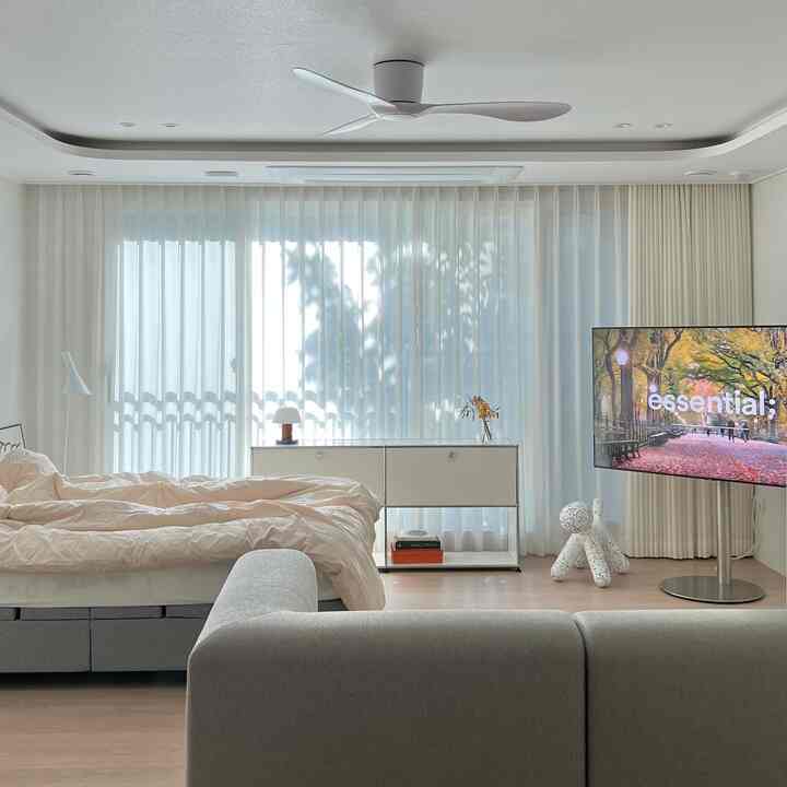 White and natural color toned bedroom featuring sofa and TV stand with a modern, cozy atmosphere