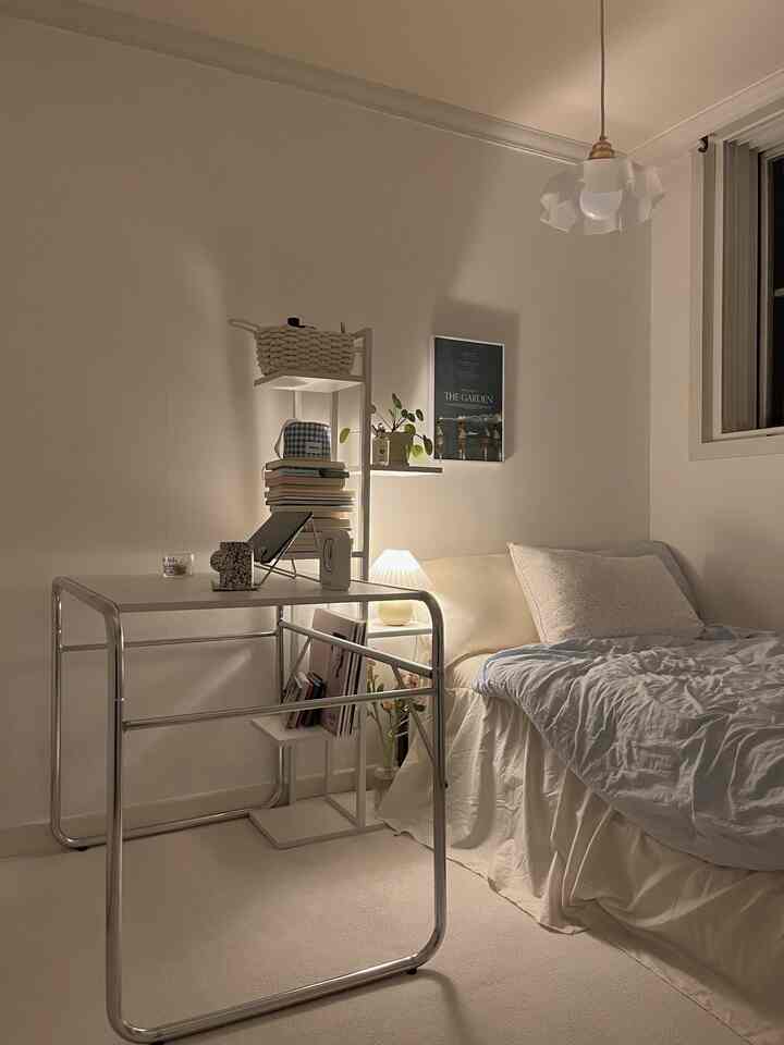 Ivory and white toned bedroom featuring a modern steel frame desk and warm lighting with a cozy atmosphere