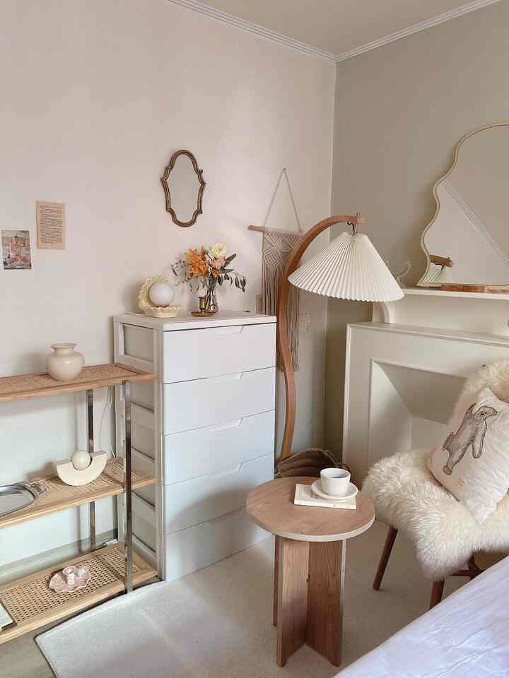 ナチュラルカラーとホワイトの配色の狭い部屋のコーナー、収納キャビネットとラグ、ヴィンテージの鏡、フロアランプが配置された雰囲気のあるインテリア