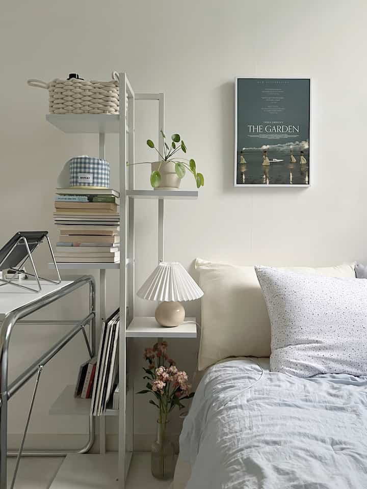 白とベージュのトーンの寝室、棚と額縁、快適な寝具が配置された自然な雰囲気のインテリア