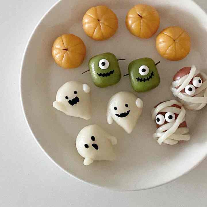 A clean home party setting featuring a white plate with orange, green, and white Halloween-themed snacks arranged adorably