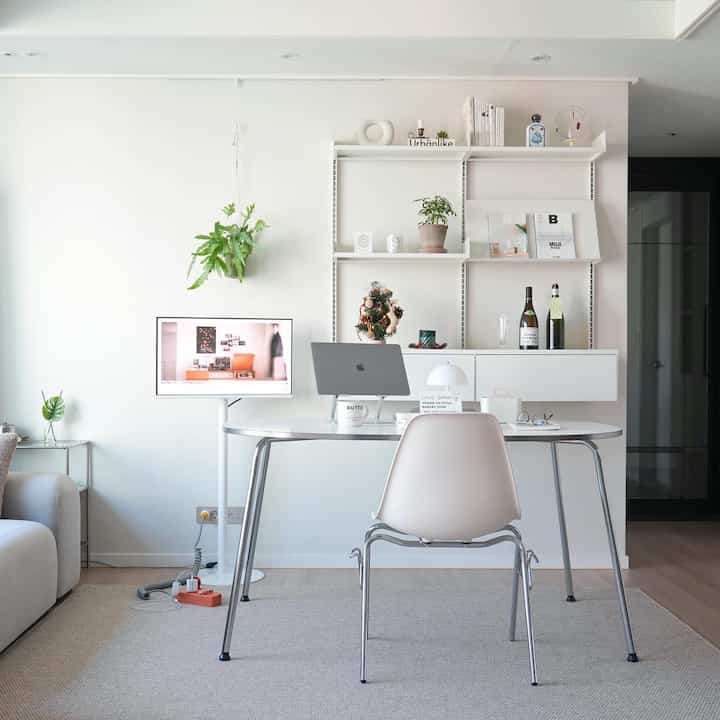 White-toned living room home office featuring a mid-century modern oval table and white chair with a clean, minimalist interior