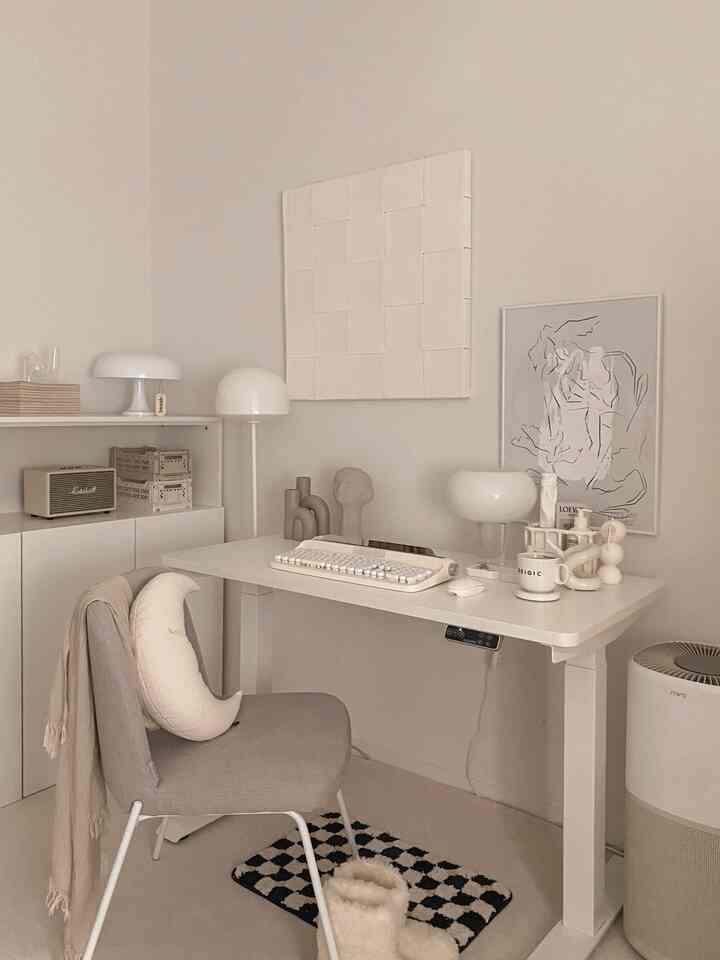 柔らかいベージュと白を基調としたホームオフィス、電動昇降デスクとミニマルなインテリアが配された清潔感のある空間