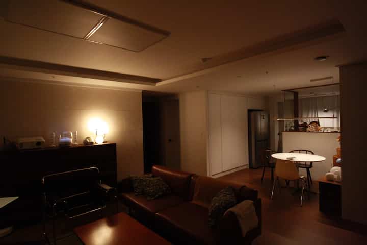 温かみのあるブラウンとナチュラルトーンのリビングとダイニング、レザーソファと丸いダイニングテーブルが配置された雰囲気のあるインテリア