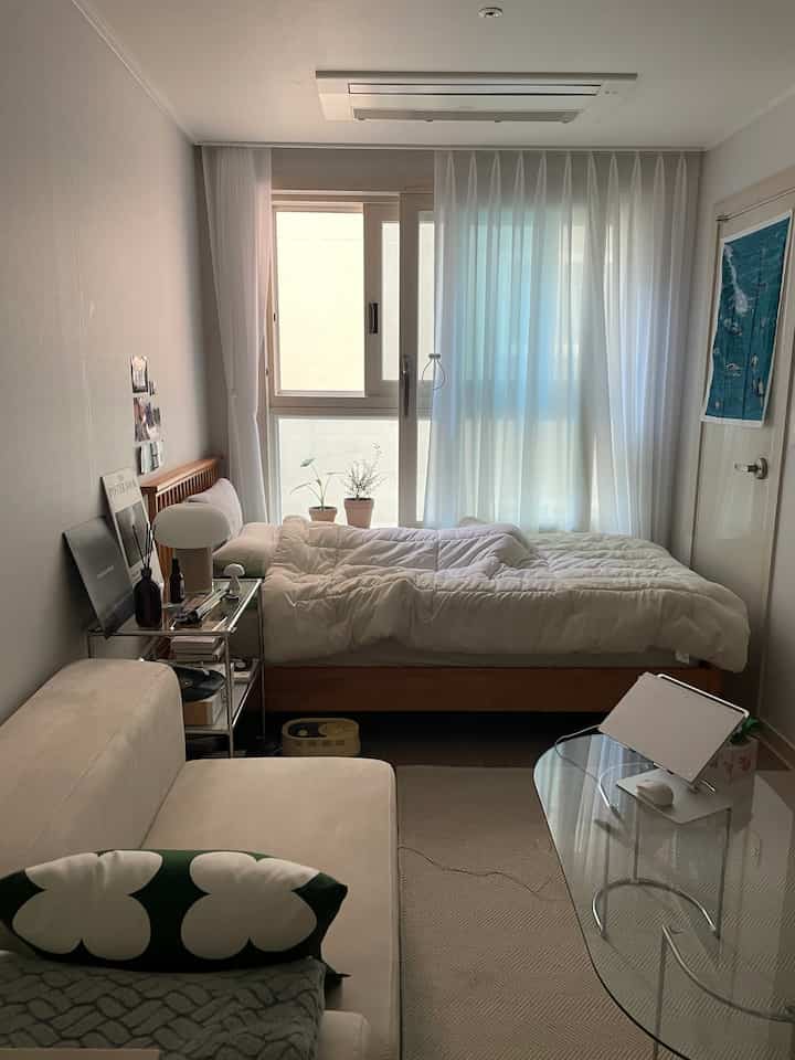 Natural beige-toned single household bedroom featuring wooden bed and sofa in a cozy space