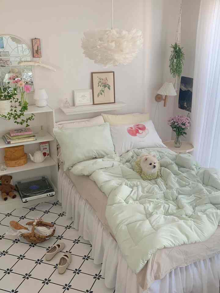 Soft mint and white bedroom featuring cozy bedding and a small dog, creating a warm and inviting atmosphere