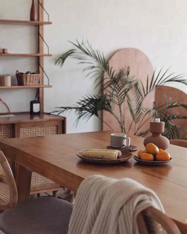 Natural wood tone kitchen dining space featuring wooden table with snacks and plates, creating a warm and cozy atmosphere