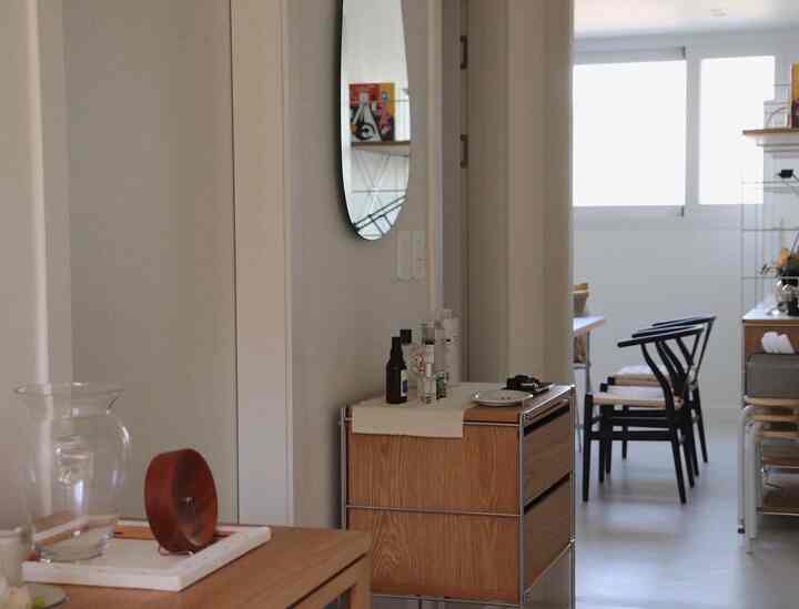 White walls and flooring in a wood tone interior living room featuring black chairs and minimal decor with a clean atmosphere