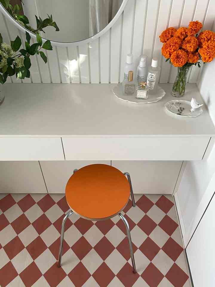 White-toned powder room featuring an orange stool and checkerboard rug with a simple vanity setup