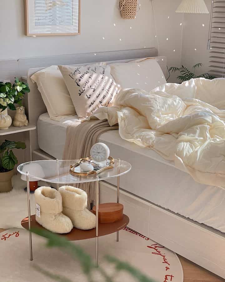 アイボリーと木目調の寝室、ナイトテーブルとポスターが配置された雰囲気のあるインテリア