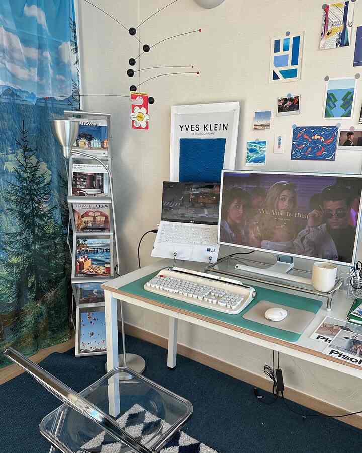 Mid-Century Modern home office in white and blue tones featuring a transparent chair, decorative mobile, and a tidy desk setup