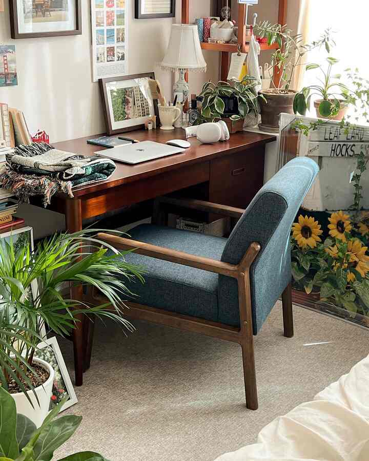 Natural toned home office space featuring wooden desk and blue armchair with cozy work setup