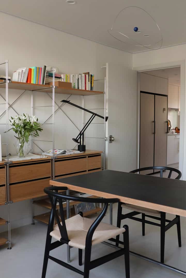 Natural tone dining room featuring a black table and wooden storage units in a simple modern setting