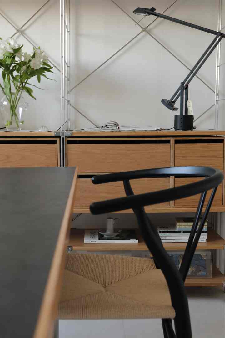 Natural wood tones and black furniture in a studio apartment space featuring a dining chair and dresser with a clean interior