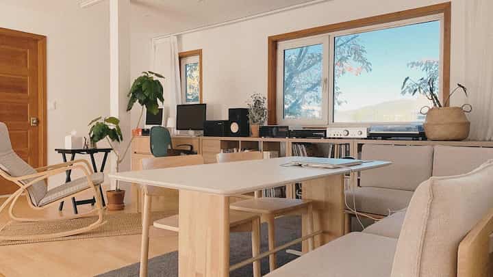 Natural-toned second-floor open study featuring a large dining table, bookshelf, and computer desks creating a cozy workspace