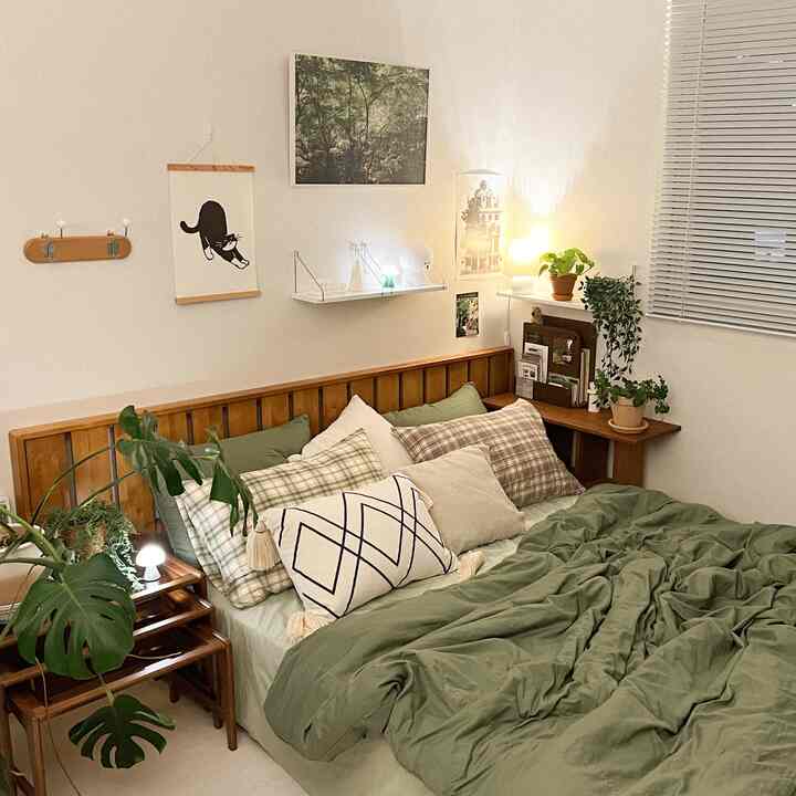 Natural wood tone and green colored bedroom featuring a bed with multiple cushions in a cozy setting