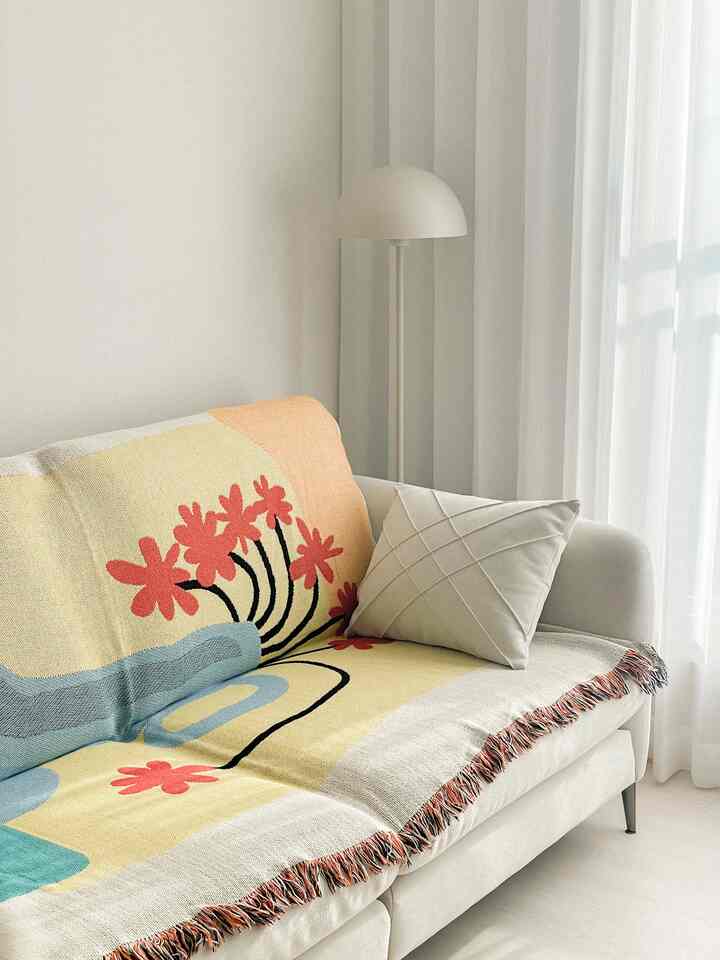 Soft white-toned living room featuring a white sofa with a floral patterned throw and cushion, creating a cozy atmosphere