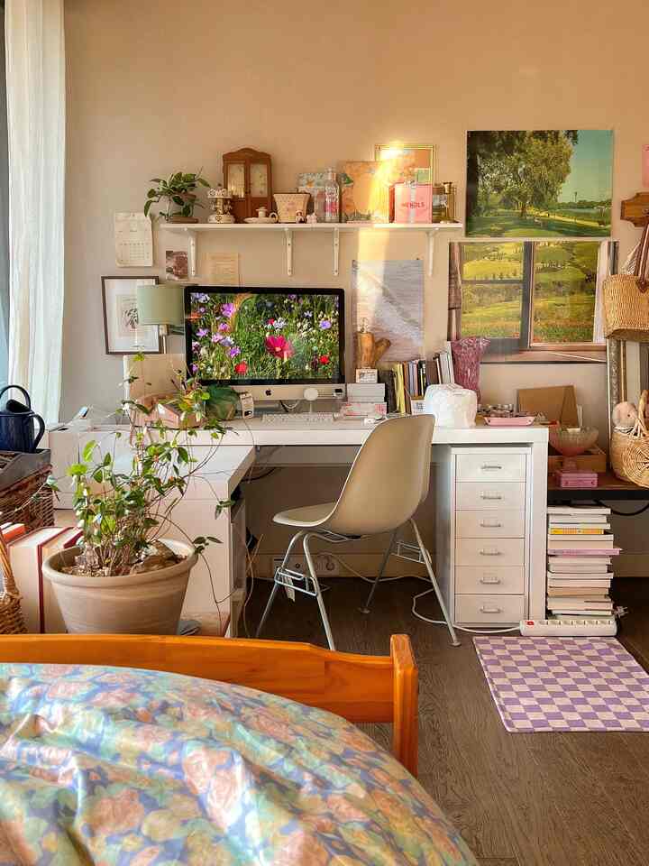 ホワイトとベージュのトーンの寝室のホームオフィス、デスクと椅子、モニター、植物が配置された温かみのある作業スペース