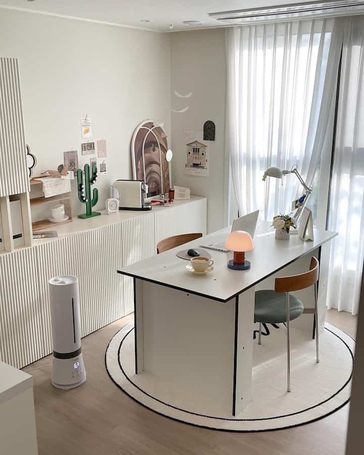 ホワイトと木目調のホームオフィス、広いデスクと加湿器、明るいカーテンが配置されたモダンな作業空間