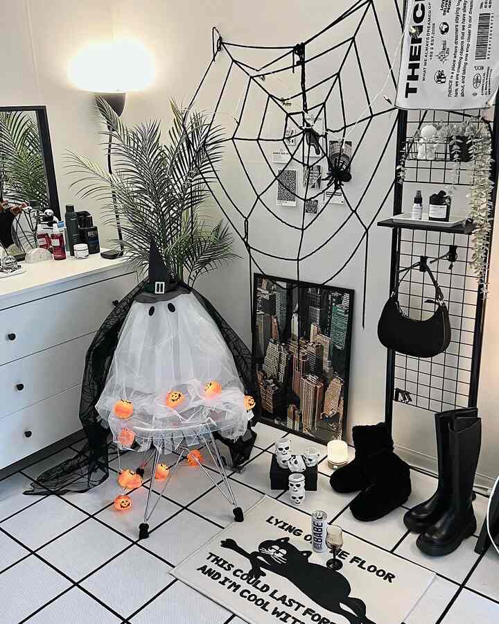 白と黒のトーンの玄関スペース、ハロウィン装飾と透明な椅子が配置されたモダンな雰囲気のインテリア