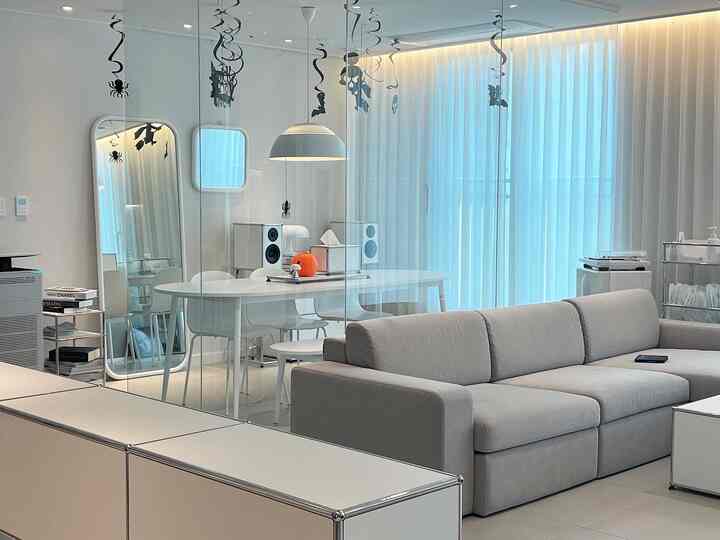 Bright white tone dining and living room featuring modern modular furniture, sofa, and Halloween decorations, creating a clean and festive atmosphere