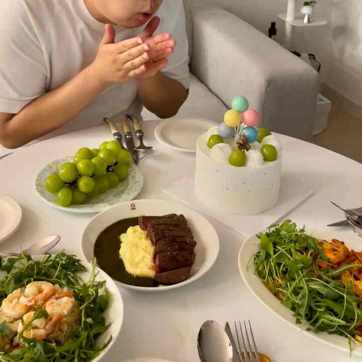 白を基調としたリビングにホームパーティー用の丸テーブルが置かれ、ケーキや料理が並ぶ温かみのある雰囲気のインテリア