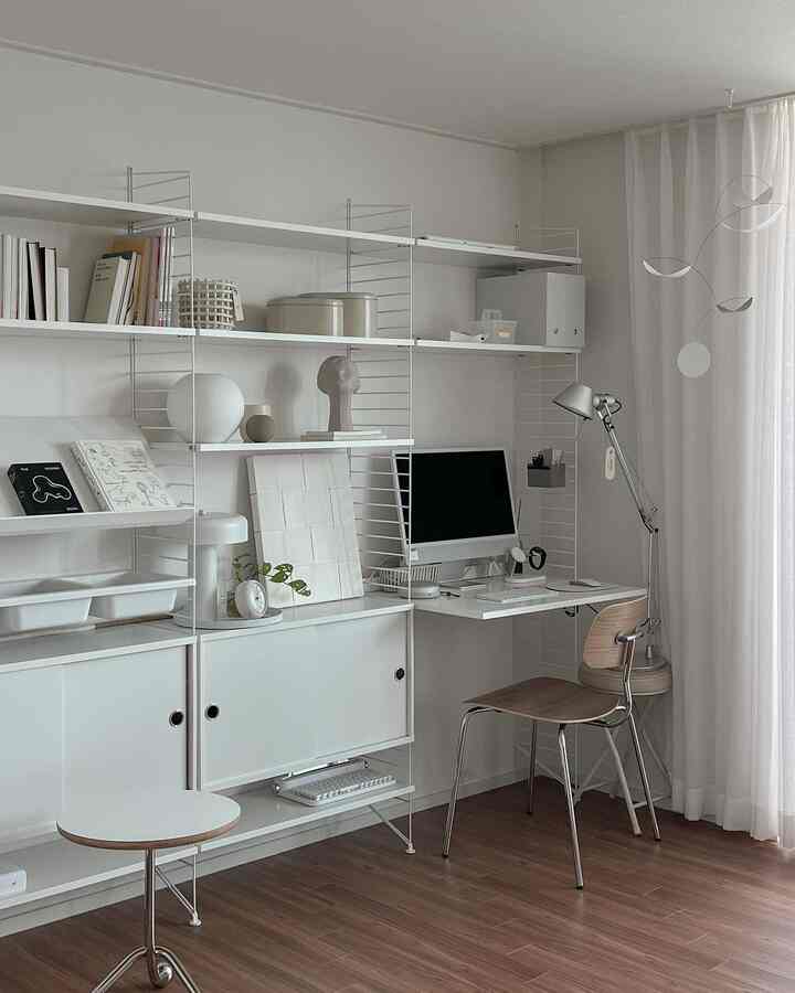 Nordic style living room study in white and wood tones featuring string system shelving, office chair, and desk in a clean setting