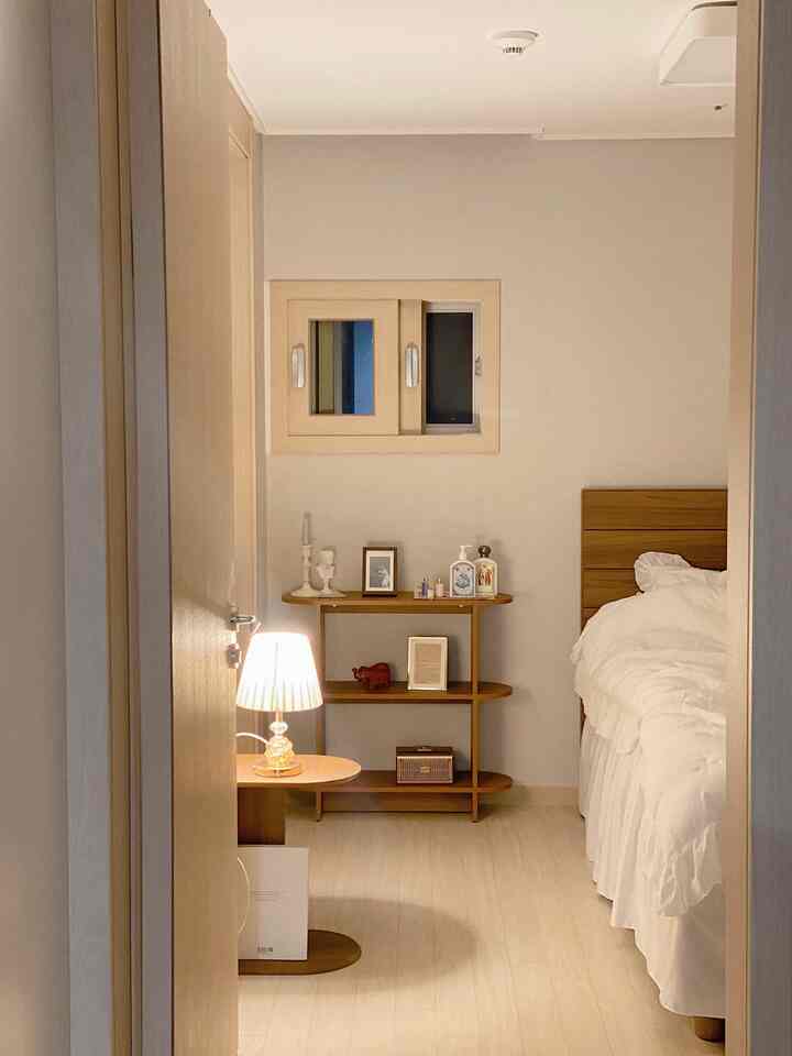 Beige-toned walls and light wood furniture in a cozy bedroom space featuring white bedding creating a calm atmosphere